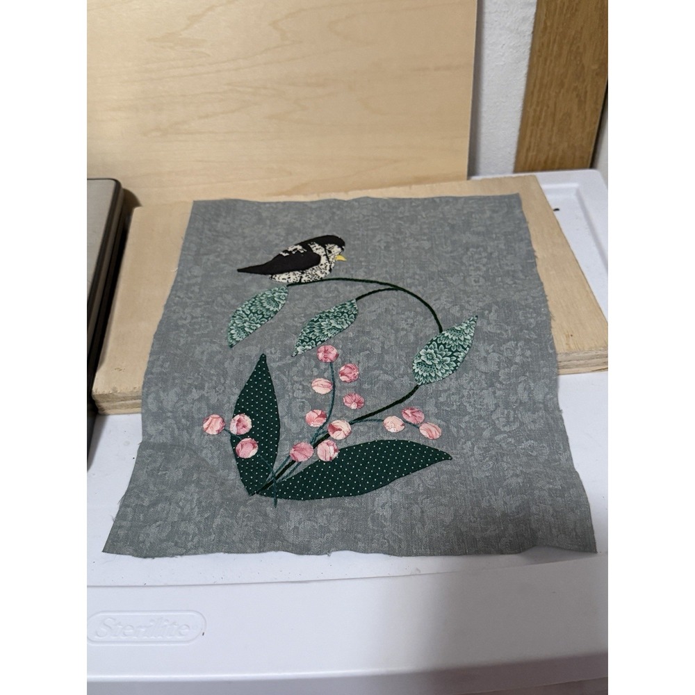handmade fabric appliqué quilt block featuring a small bird perched on a branch